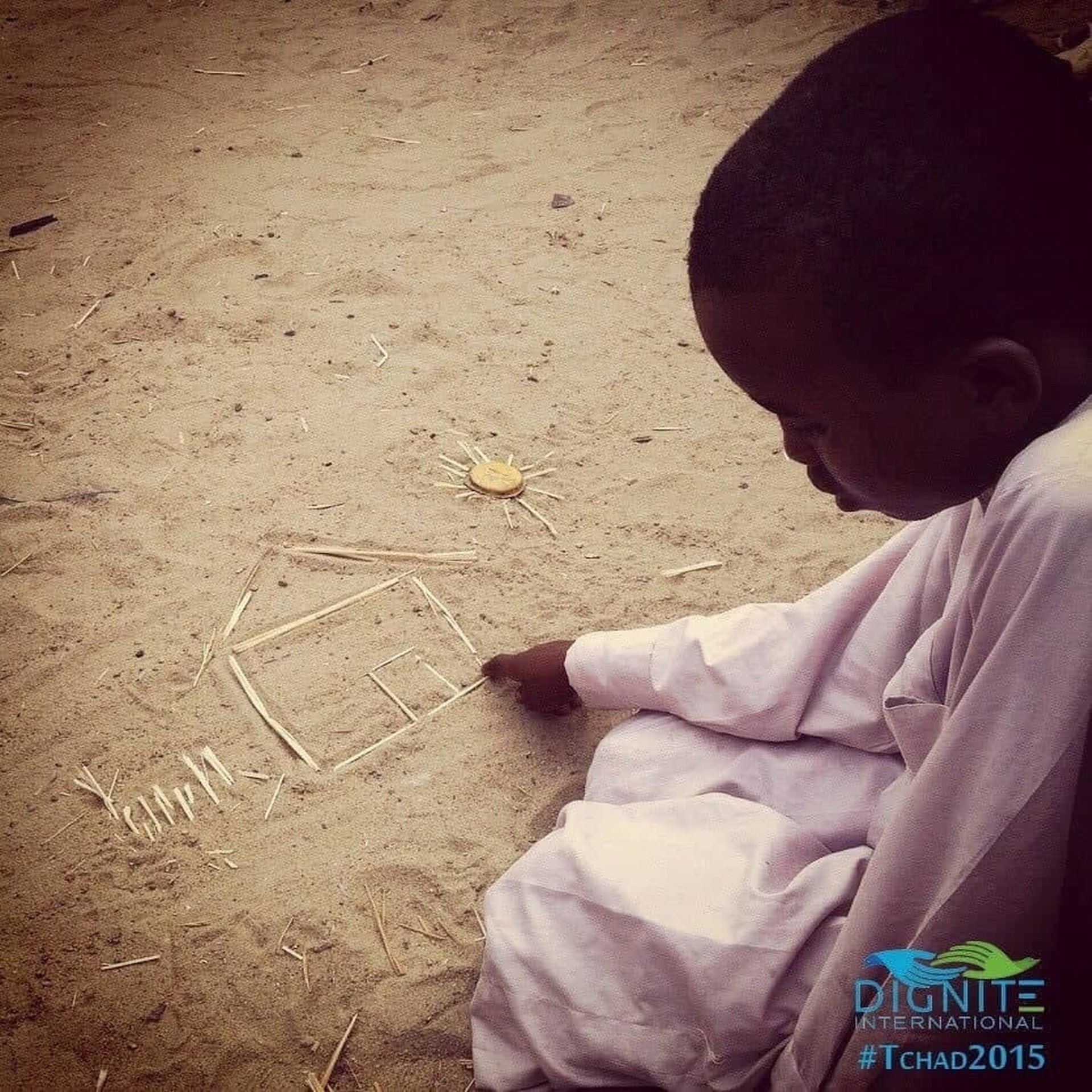 Enfant africain qui dessine une maison sur le sable apportons lui une aide humanitaire au Tchad