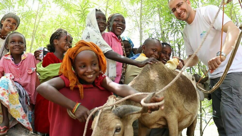 Enfants africains avec un bélier et un humanitaire de l'ong d'Afrique Dignité international souriants